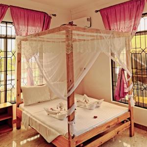 a bedroom with a canopy bed and windows at Raha house in Nungwi