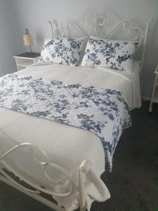 - un lit blanc avec des draps et des oreillers bleus et blancs dans l'établissement Mangaroa, farmstay, à Upper Hutt