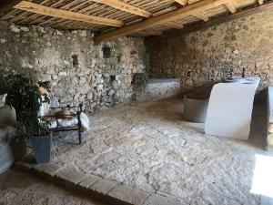 a room with a stone wall with a refrigerator at oliveraie de caractère in Noto