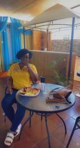 a woman sitting at a table with a plate of food at SherNette Nest. in San Juan