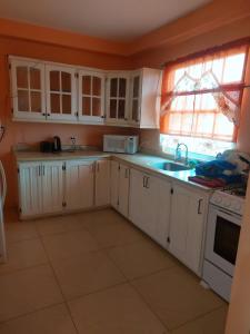 eine Küche mit weißen Schränken, einem Waschbecken und einem Fenster in der Unterkunft SherNette Nest. in San Juan