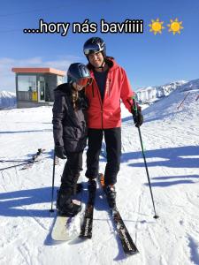 dwoje ludzi stoi na nartach w śniegu w obiekcie Apartmán Horní Mísečky F11 - Horský svět w mieście Horni Misecky