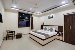 a bedroom with a bed and a chair and a window at Capital O Hotel Pink Peral in Jaipur