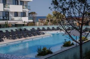 a swimming pool with lounge chairs next to a building at DAMAR Infinity Beach and Pool Mamaia- private parking in Mamaia Sat/Năvodari