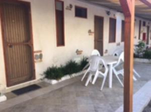 un patio con sedie bianche e un tavolo di fronte a un edificio di Residence La Quiete a Taureana