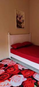a bedroom with a bed with red sheets and a red pillow at Barokah Homestay Kijal in Kijal