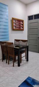 two wooden chairs and a table in a room at Barokah Homestay Kijal in Kijal