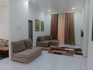 a living room with two couches and a television at Barokah Homestay Kijal in Kijal