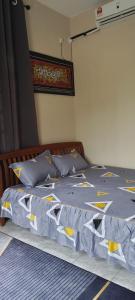 a bed with a blue and yellow comforter and pillows at Barokah Homestay Kijal in Kijal