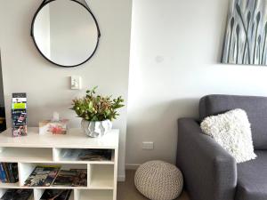 a living room with a chair and a mirror at Hobart Inner City Apartment in Hobart
