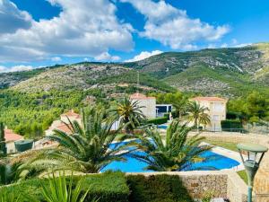 une villa avec une piscine et des palmiers dans l'établissement Precioso ático en la Sierra de Irta, à Alcossebre