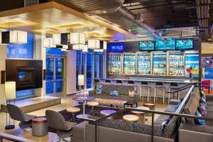 a lobby with couches and a bar with televisions at Aloft Denver Airport at Gateway Park in Aurora