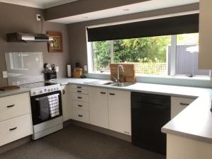 a kitchen with white cabinets and a sink and a window at River Heights in Taupo