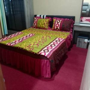 a bedroom with a bed with a green and pink blanket at Aqiza Home Kuala Krai in Kuala Kerai
