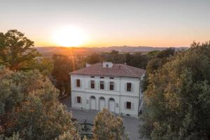 ein weißes Haus mit Sonnenuntergang im Hintergrund in der Unterkunft Villa Cosmiana suites in Peccioli