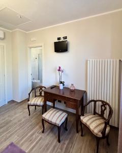 a room with a desk and two chairs and a television at Agriturismo EdMo in Castiglione Tinella