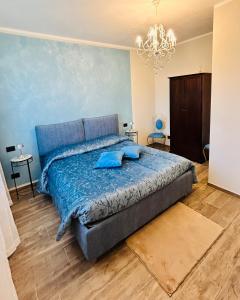 a bedroom with a bed with blue sheets and a chandelier at Agriturismo EdMo in Castiglione Tinella