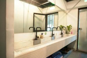 Baño con 3 lavabos y espejo en Meeting Mates Hostel, en Taipéi