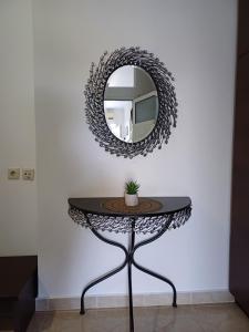 un miroir rond sur un mur blanc avec une table dans l'établissement Artemisia Apartment, à Koskinou