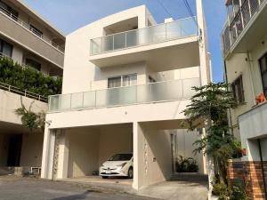 那覇市にあるVacation Rental Kally Naha Okinawaの建物前に駐車した白車