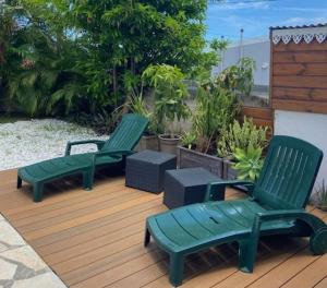 two green chairs sitting on a wooden deck at La Kaz Pomme Cannelle in Rivière