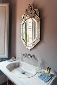 ein Bad mit einem Waschbecken und einem Wandspiegel in der Unterkunft Villa Cosmiana suites in Peccioli