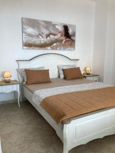 a bedroom with a large white bed with a painting on the wall at Panorama Pearl in Balchik