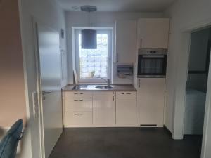 a kitchen with white cabinets and a sink and a window at Anides in Dillingen an der Donau