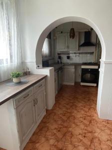 a kitchen with white cabinets and an archway in it at Magyar Lovasvendégház in Szilvásvárad