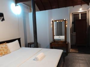 - une chambre avec un lit blanc et un miroir dans l'établissement Rosanuka Beach Villa, à Wayikkal