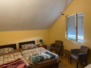a bedroom with two beds and two chairs and a window at Guest house Vukovic in Podgorica