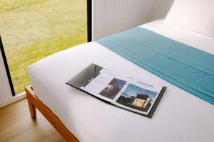 a magazine sitting on a bed with a window at Rimu View 1 in Hokitika