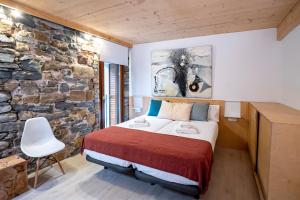 a bedroom with a bed and a stone wall at Aristondo Pentsioa in Getaria