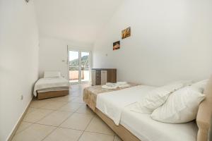 Un dormitorio blanco con una cama grande y una ventana en Vila lux Rajović, en Budva