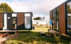 a person standing on a bench outside of a tiny house at Rimu View 1 in Hokitika