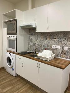 eine weiße Küche mit einer Spüle und einer Mikrowelle in der Unterkunft PRADALONGO in Madrid