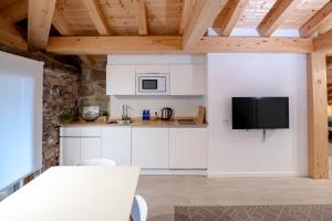 a kitchen with white cabinets and a flat screen tv at Aristondo Pentsioa in Getaria