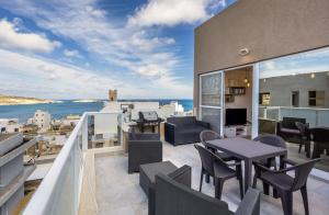 d'un balcon avec des tables et des chaises et une vue sur l'océan. dans l'établissement ST PAUL'S BAY NEW MODERN PENTHOUSE 2 MINUTES FROM BEACH Seascape Stays, à San Pawl il-Baħar