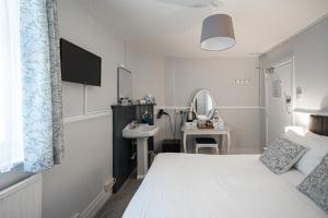 1 dormitorio con cama blanca y lavamanos en Gresham Guest House, en Weymouth