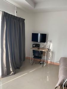 a room with a desk with a computer and a television at Superb studio Apartment in Ban Na Khua