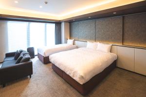 a hotel room with two beds and a couch at GOLD STAY Nagoya Osu in Nagoya