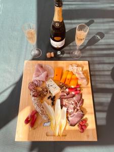 una tabla de cortar con carne y queso y dos copas de vino en Belgica-Melay 52400, en Melay