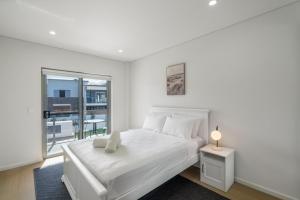 um quarto branco com uma cama branca e uma janela em Relax at Ridgewaters em Kiama