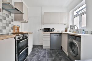 a kitchen with white cabinets and a washer and dryer at Beautiful 3 Bedroom Home Renovated Centrally Located in South Wales in Caerphilly