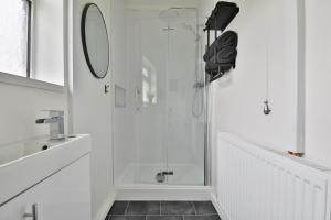 a white bathroom with a shower with a glass door at Beautiful 3 Bedroom Home Renovated Centrally Located in South Wales in Caerphilly