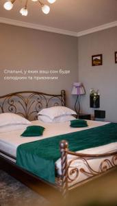 a bedroom with a large bed with green sheets and pillows at Кузня міні-готель in Mateyevtsy