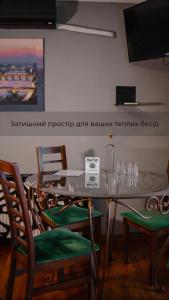 ein Esszimmer mit einem Tisch, Stühlen und einem TV in der Unterkunft Кузня міні-готель in Mateyevtsy