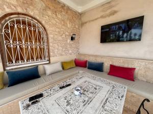 een bank met kleurrijke kussens en een televisie aan de muur bij Chalet Berbère in Essaouira