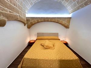 Cama en habitación con pared de ladrillo en Agnese Experience Suite en Gallipoli