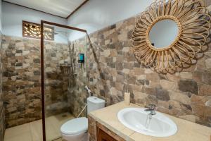 a bathroom with a sink and a toilet and a mirror at Munduk Farmhouse in Munduk